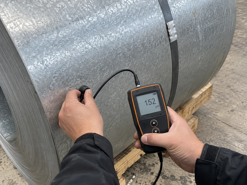 A coating mass check being made on a galvanized coil, the instrument reading visible.