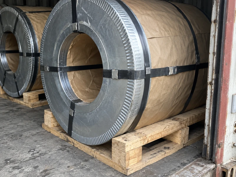 Galvanized coils with steel edge protectors and moisture-proof paper on wooden pallets, strapped for loading.