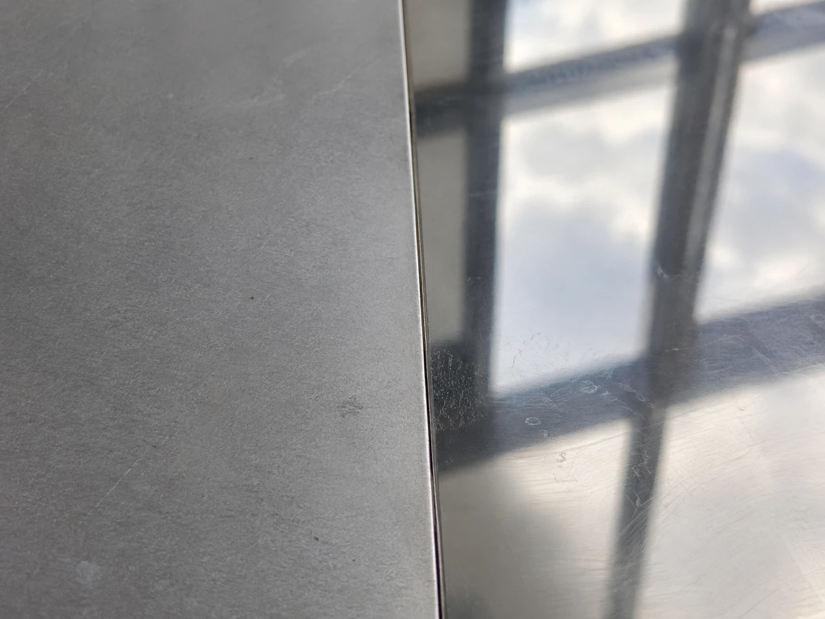 A 2B sheet and a BA sheet edge to edge, the matte grey face against the mirror-bright one.