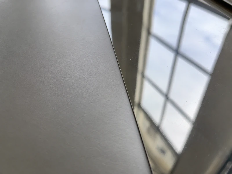 The same reflected window on a 2B surface and on a BA surface, blurred on one and sharp on the other.