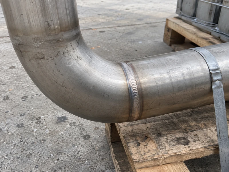 A welded stainless steel pipe joint, the weld bead even and the surface unpolished.
