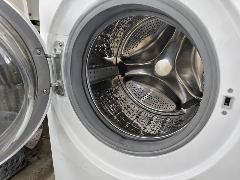 The bright stainless steel drum inside a washing machine, no brand marks visible.