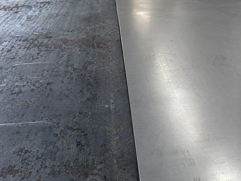 A hot rolled surface and a cold rolled surface side by side, dark mill scale against smooth grey.
