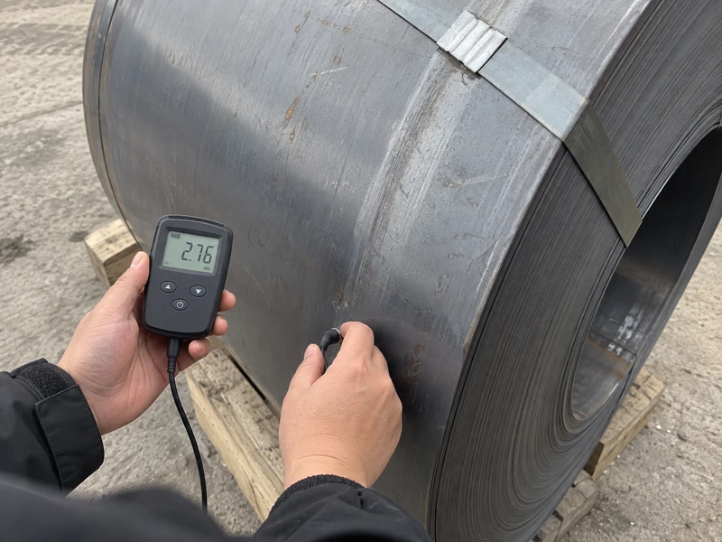 A Q235B coil being measured before shipment, the instrument reading visible.