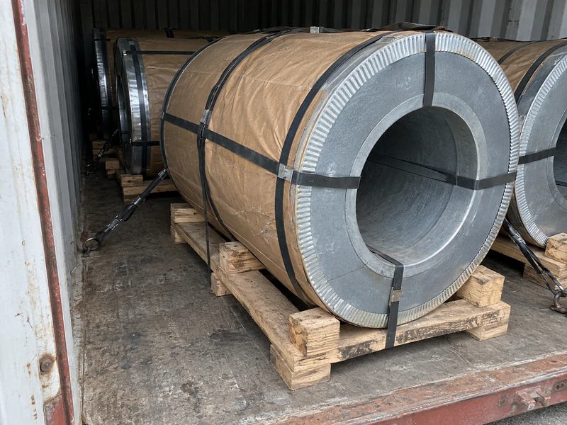Galvanized coils with edge protectors and moisture-proof paper on pallets, strapped inside a container.