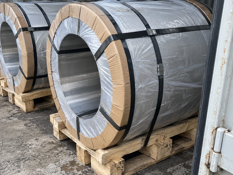 Stainless coils on pallets in moisture-proof wrapping with edge protectors, strapped for shipment.